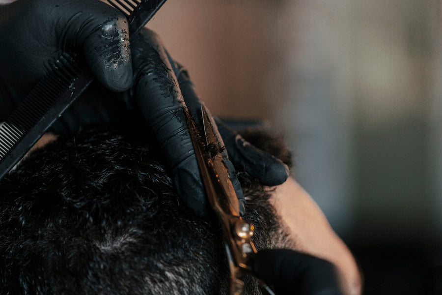 A barbers hands trim a customers hair