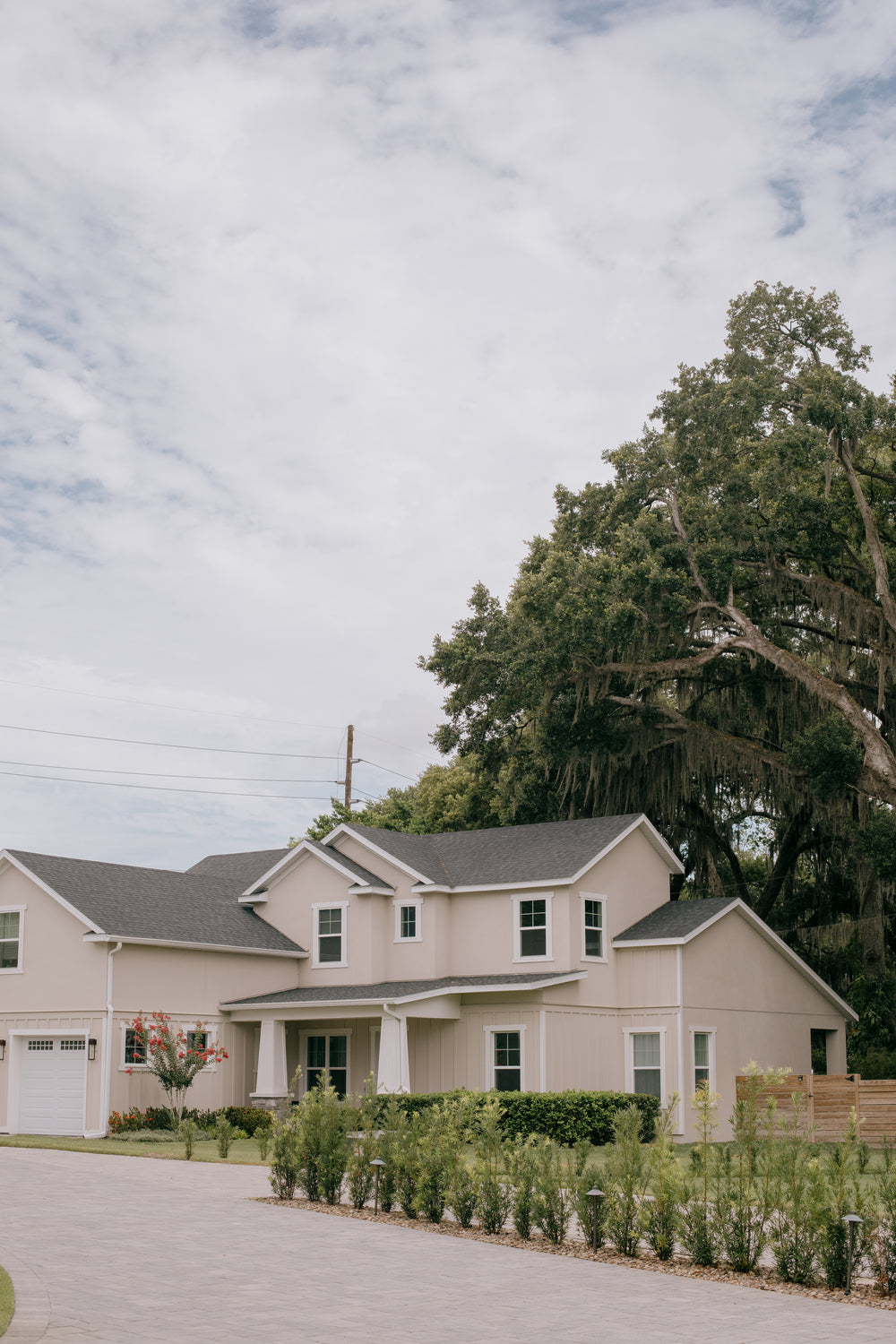 a beige house with a grey roof and large trees