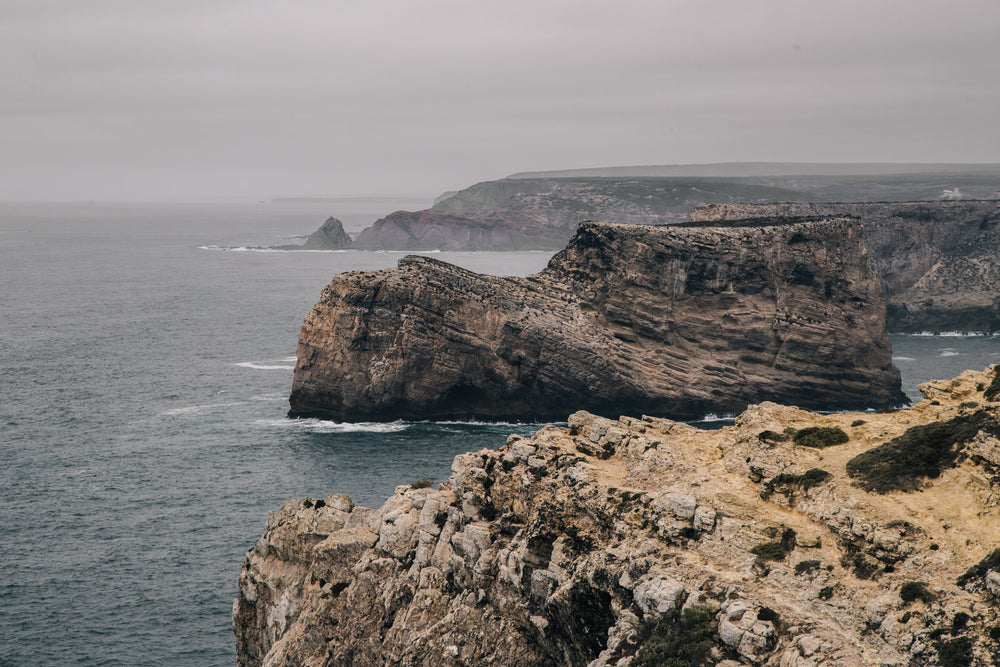 a big stone outcrop stands apart from cliffs in the grey sea