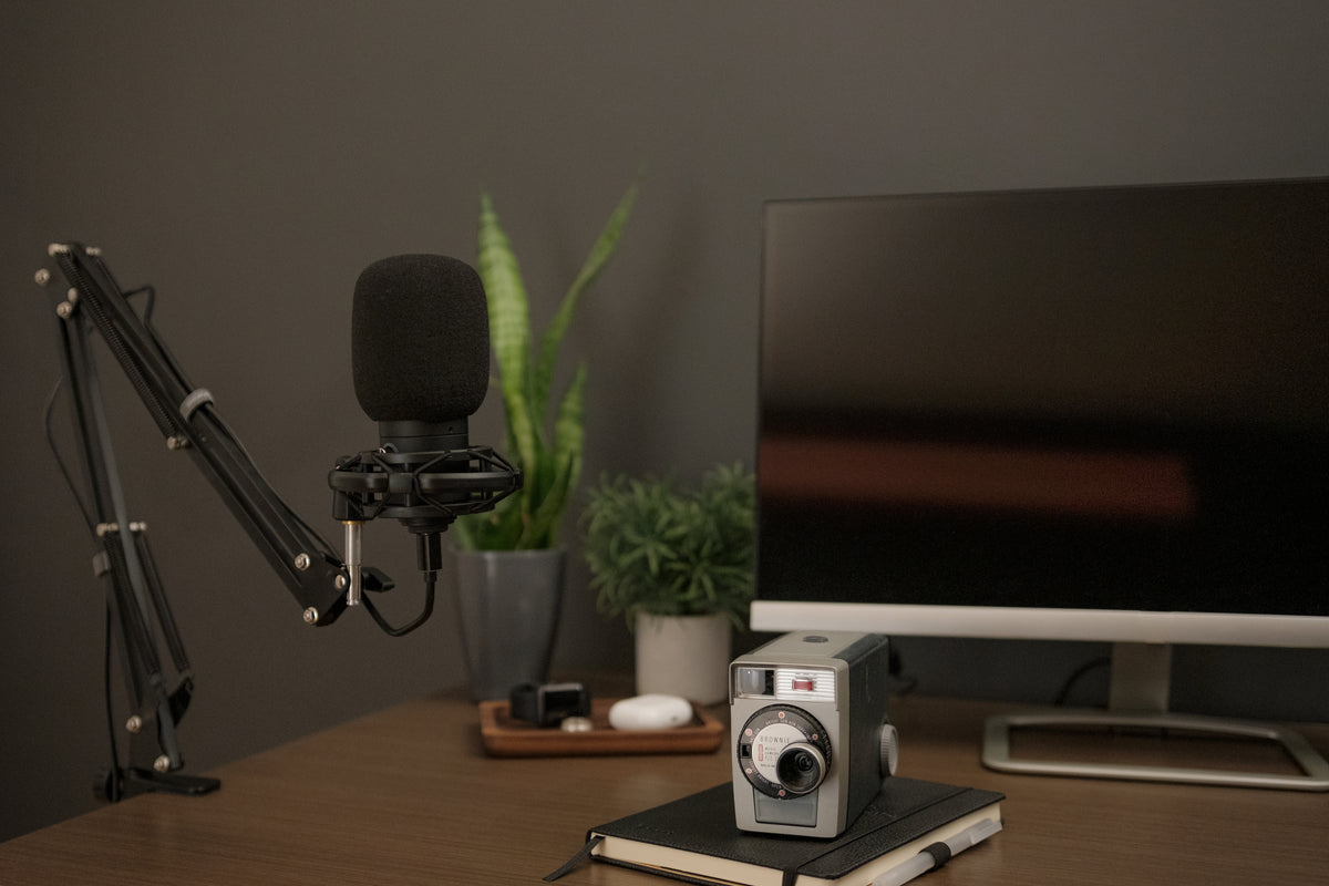 um microfone condensador ao lado de um computador desktop e uma câmera vintage