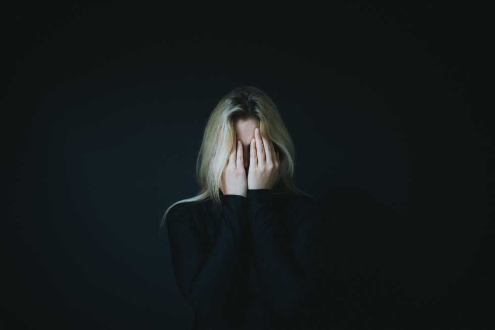 a blond woman hold her hands up to hide her face