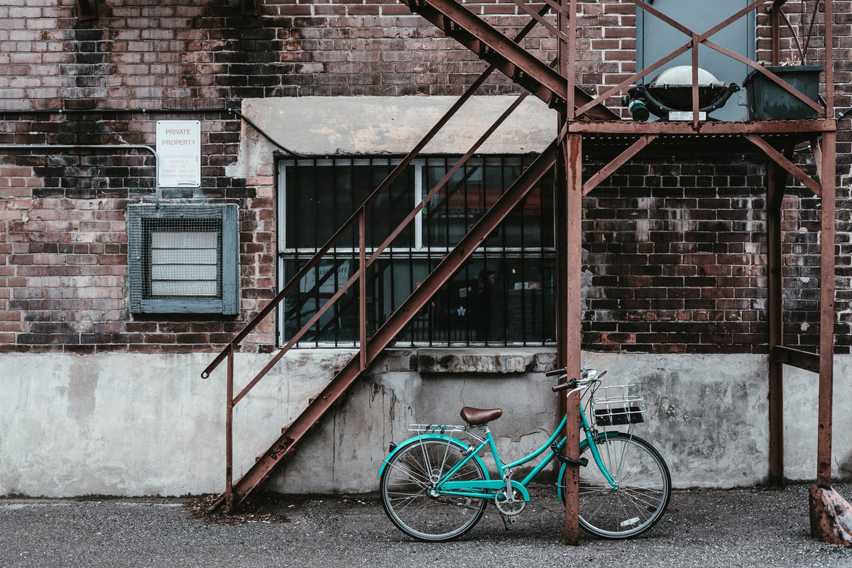 a blue bicycle against a rusty apartment fire escape