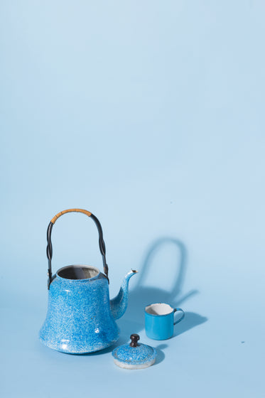 a blue kettle and mug against a blue background
