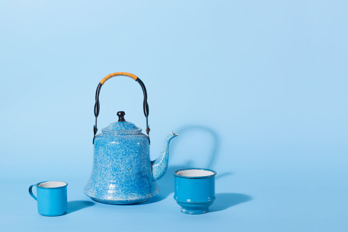 a blue kettle and tin mug against a blue background