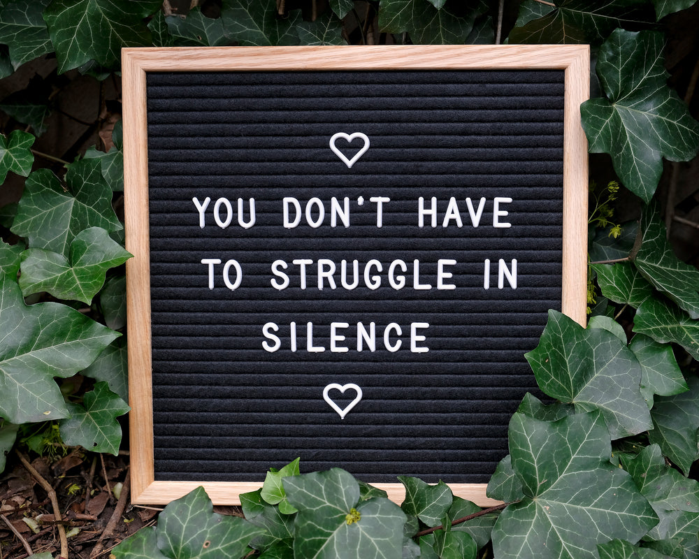 a board with white plastic text is surrounded by ivy