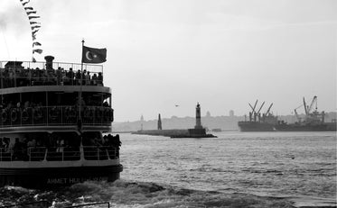 a boat full of people sailing away in black and white