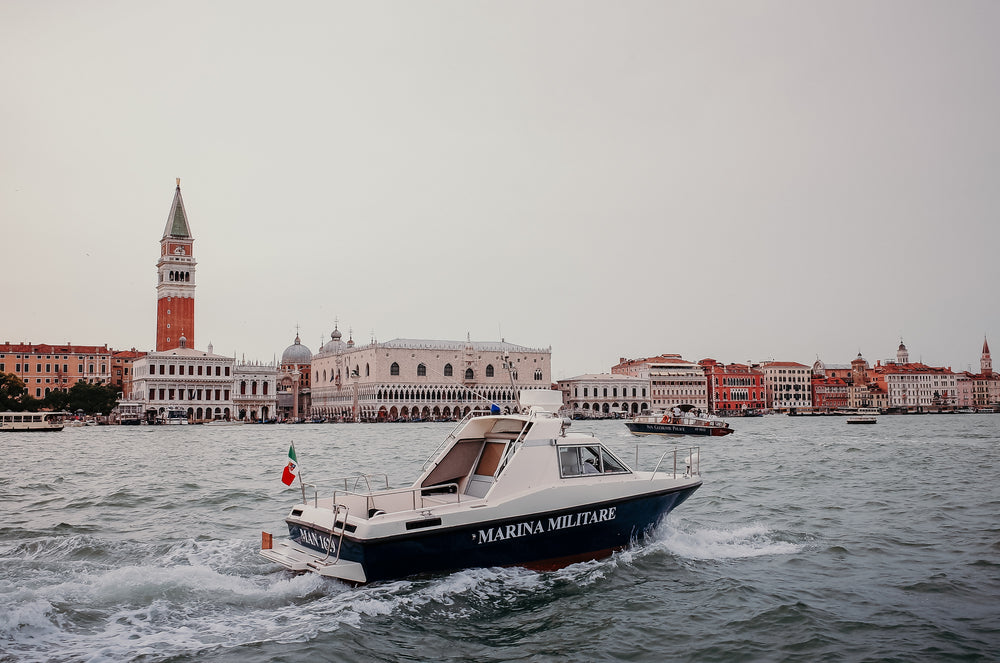 a boat on wavy water with buildings in the distance