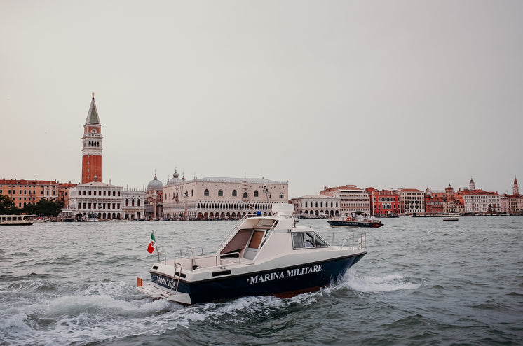 A Boat On Wavy Water With Buildings In The Distance