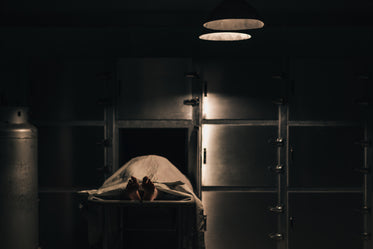 a body sits in a slider under a blanket in the morgue