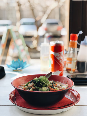 a bowl of ramen by a restaurant window