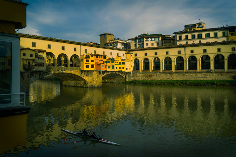 A Bridge Over A River With Yellow Buildings Lining It