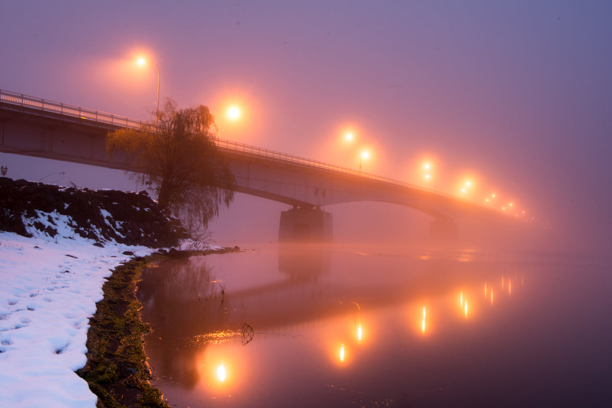 a bridge with yellow lights blurred by thick fog