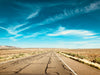 a bright blue sky over a cracking desert highway