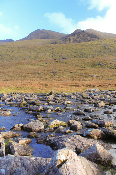 a bubbling river in front of rolling hills