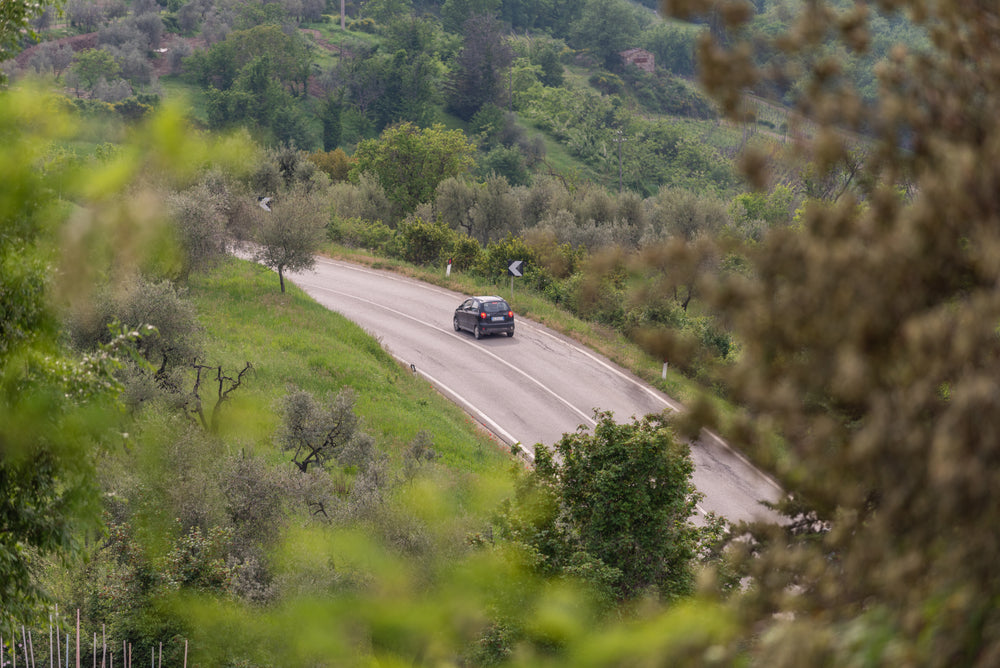 a car winds round a curve on a highway on a hill