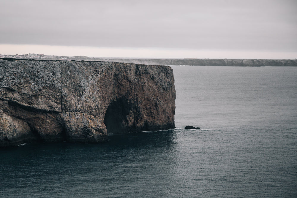 a cave gulps in icy water out the side of a cliff