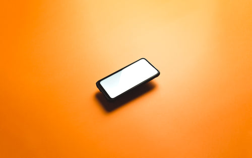 a cellphone floats in the middle of orange background