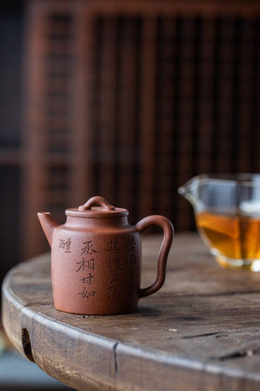 a ceramic teapot on a wooden table with chinese characters