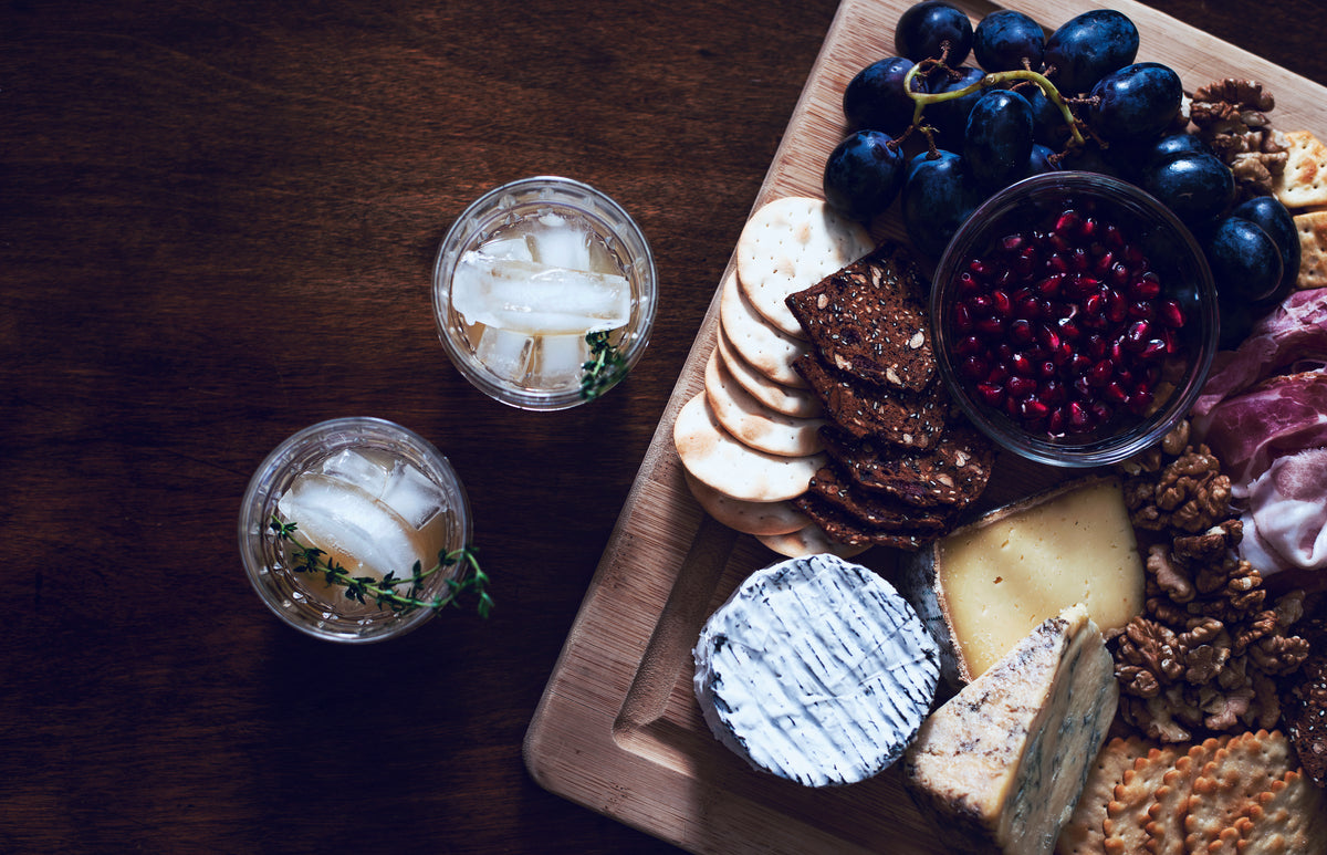 a cheese and fruit board with cocktails