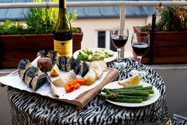 a cheese board and wine on a balcony at sunset