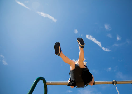 a child on a swing under a blue sky