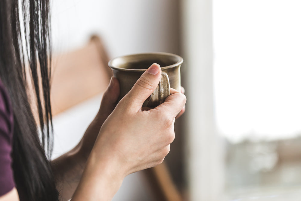 a close up of a woman holding a coffee cup