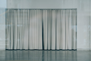 a closed grey curtain surrounded by a grey wall