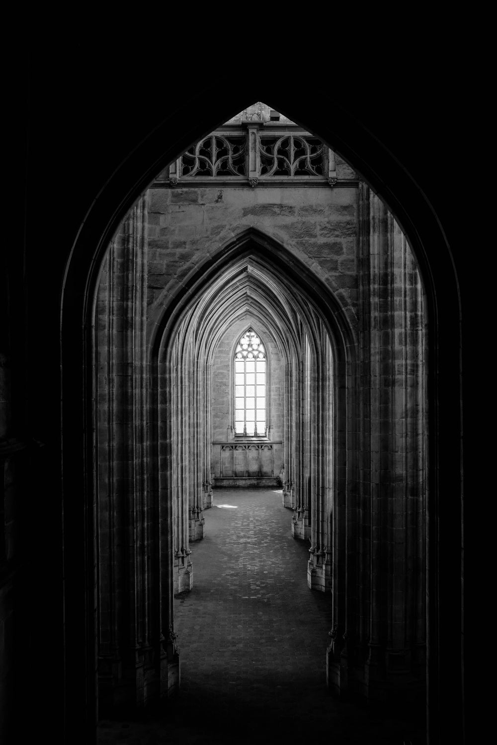 a corridor of archways leads to a gothic window