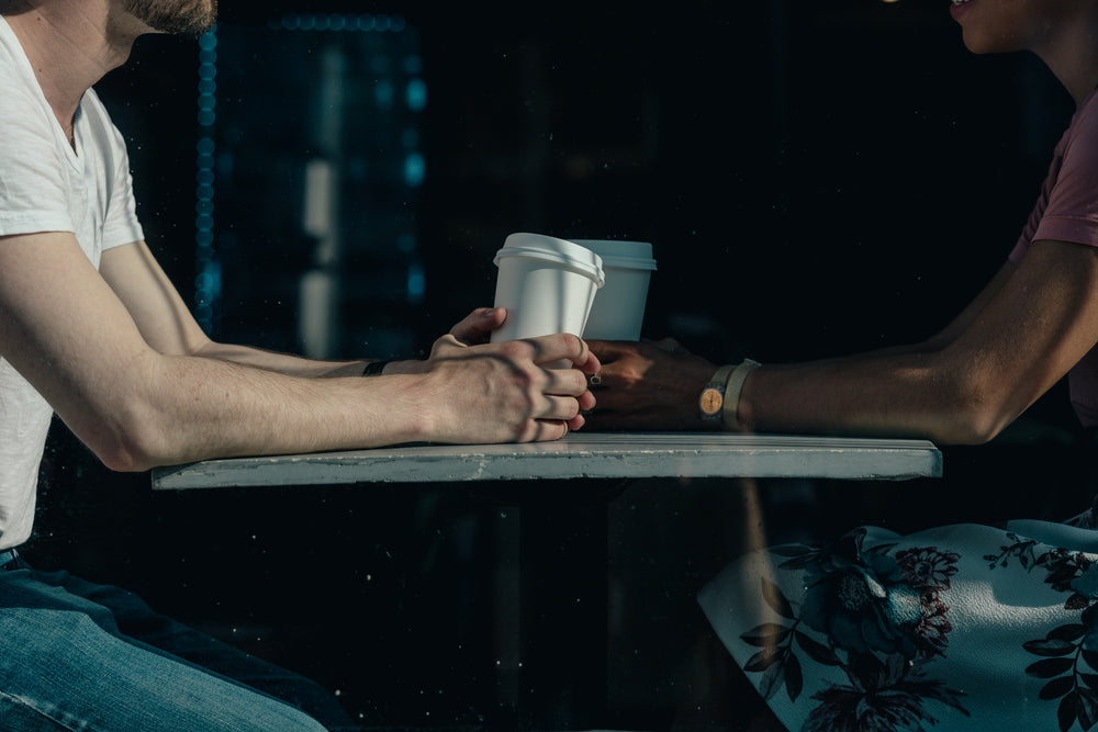 a couple chat over coffee cups on a sunny day in a cafe