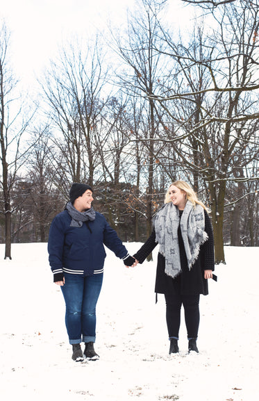 a couple hold hands while walking through the snow