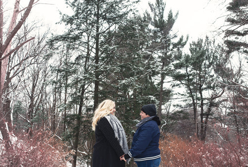 a couple holding hands stands in the snow
