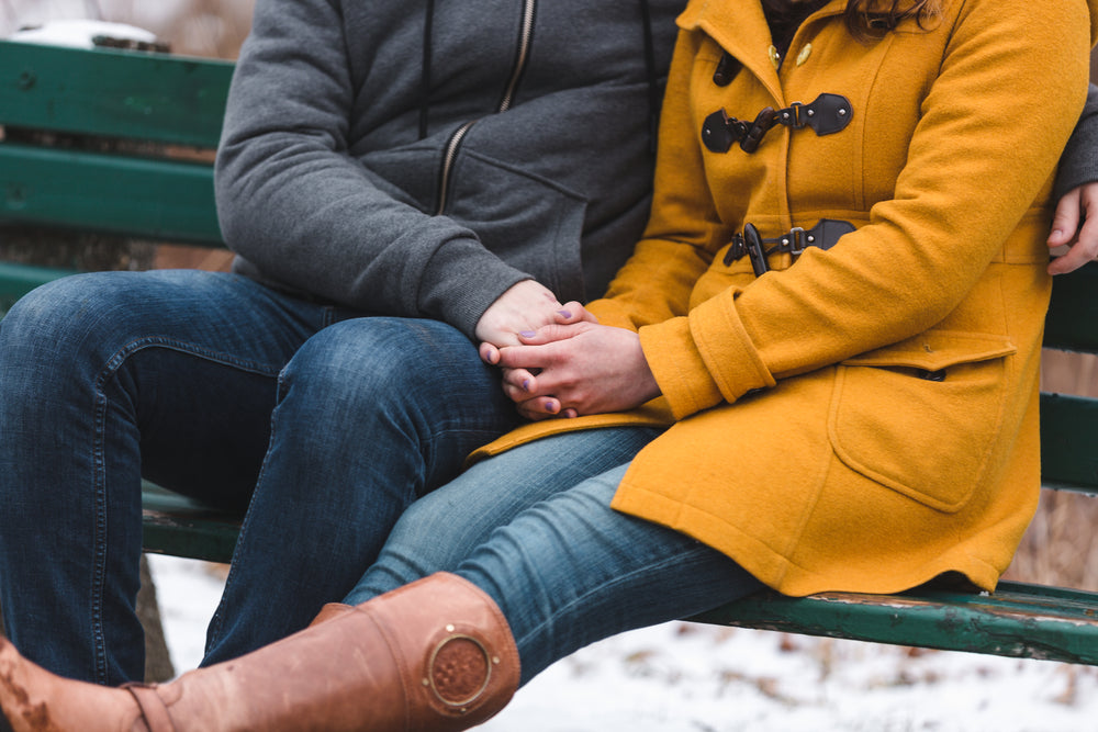 a couple huddles for warmth on a bench