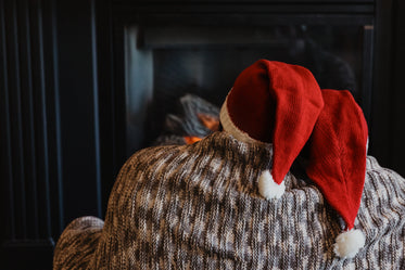 a couple in santa hats sits by the fireplace