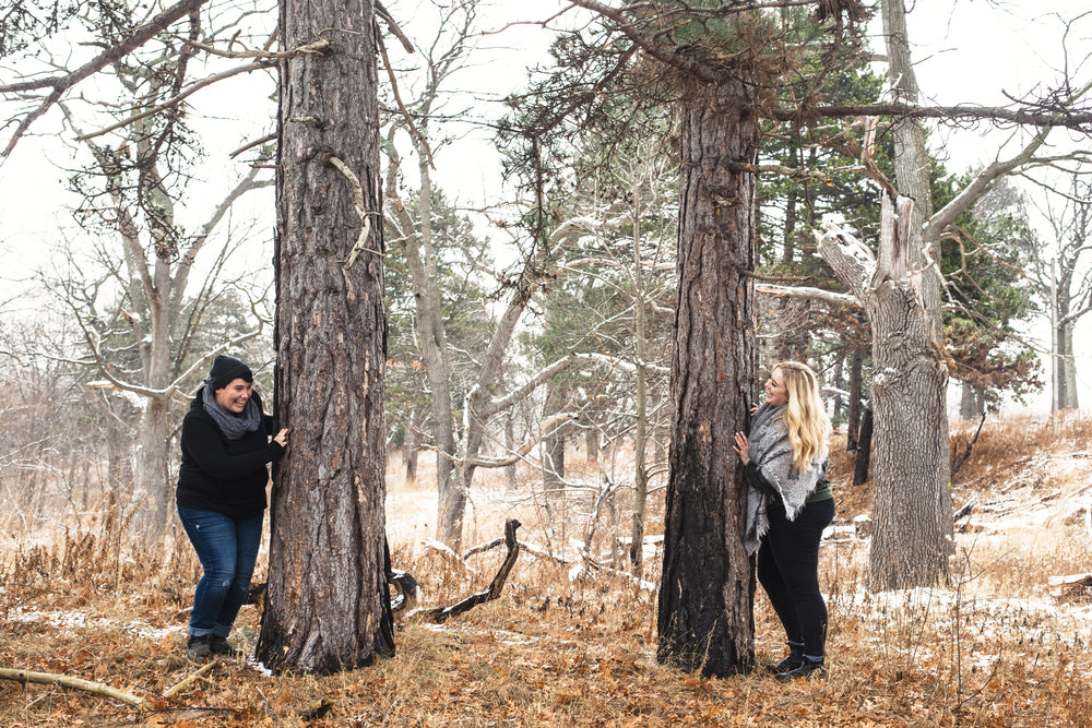 a couple laugh together between trees