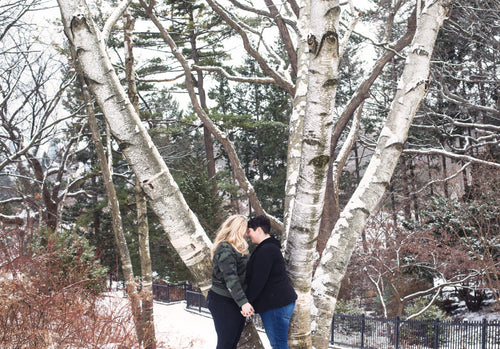 a couple share a moment under snow covered trees