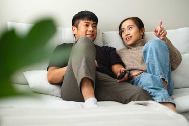 a couple sit on a their couch in conversation