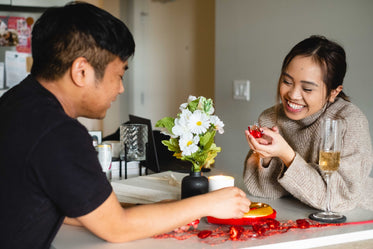 a couple sits across from each other sharing chocolates