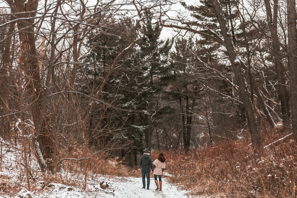 a couple strolls through a snow-covered forest