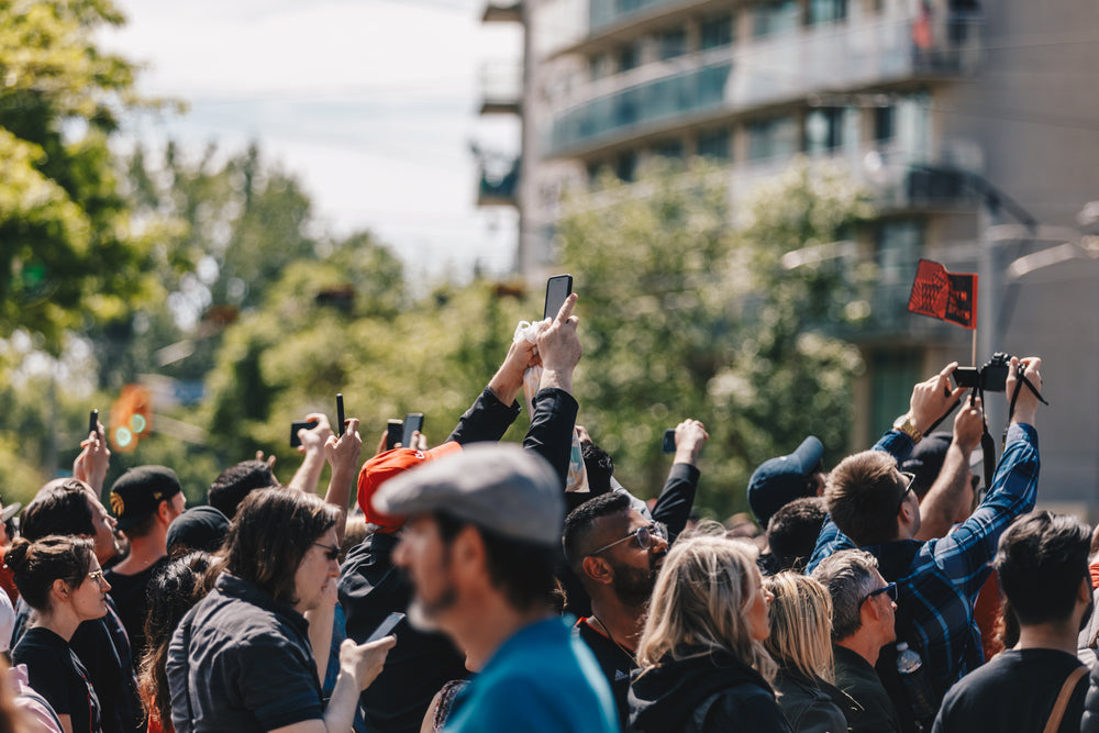 a crowd holds up their phones in the sun