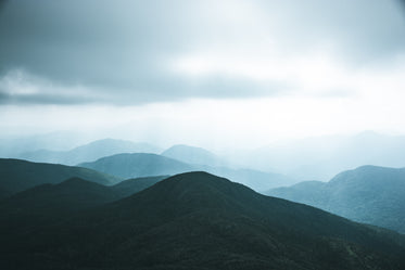 a dark green hill against the smoky sky