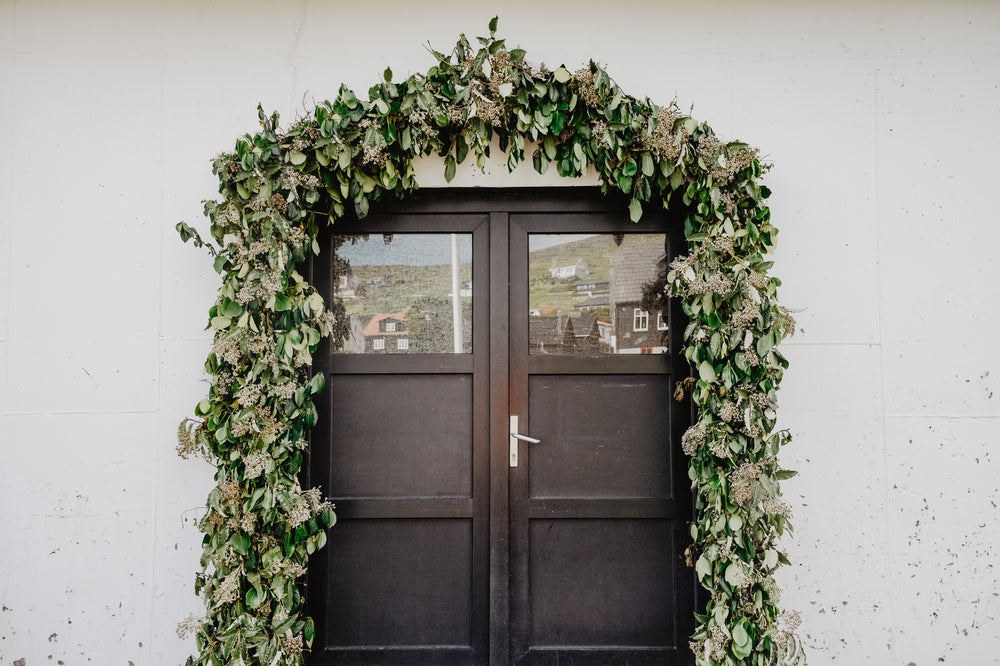 a dark wooden doorway framed by a trellis of greenery