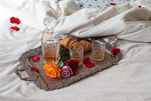 a decanter and croissants on a silver tray