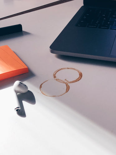 a desktop covered in laptop, coffee stains and post it notes