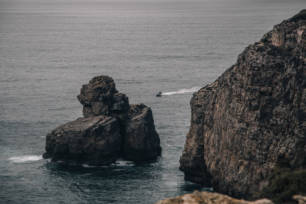 a dinghy cuts through the grey sea