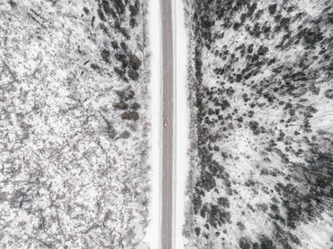 a drone view of a red pickup truck on a road surrounded by forest