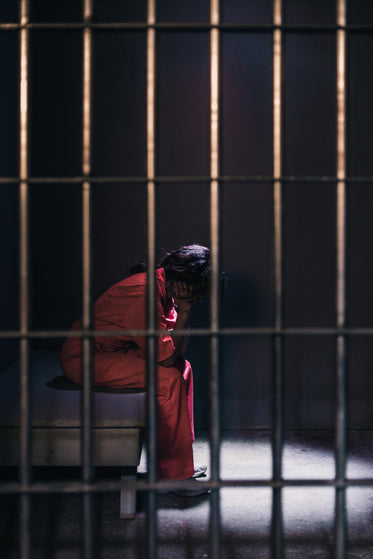 a female prisoner sits on her cell bed with head in hands