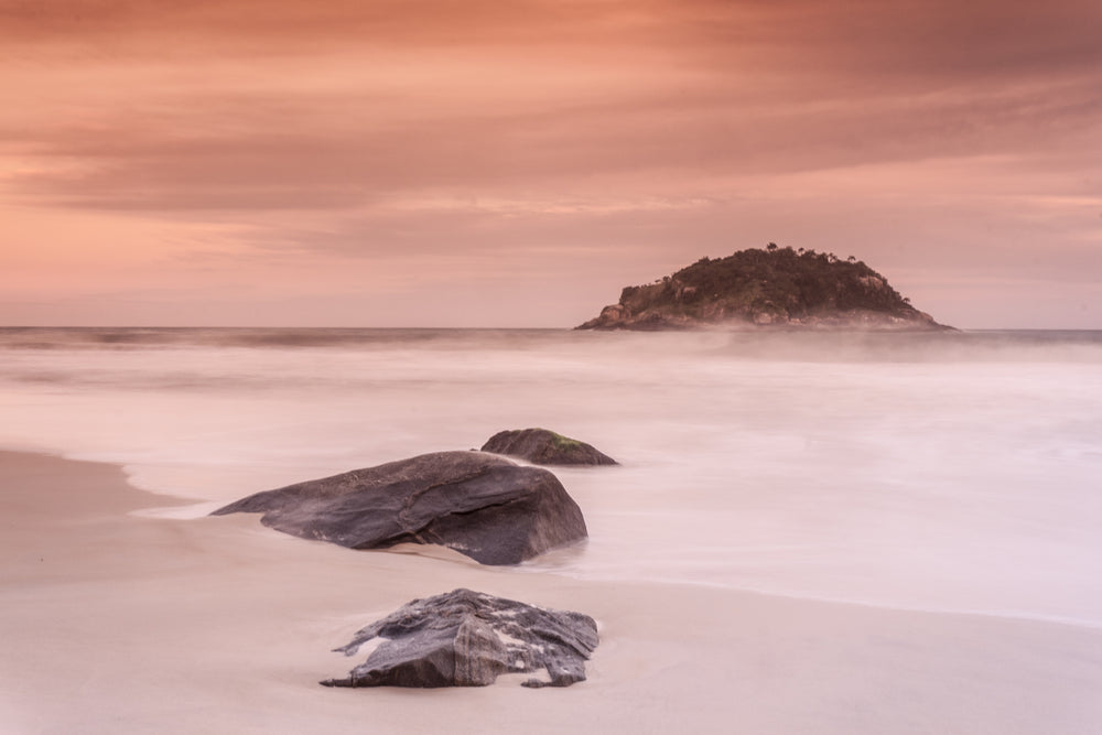 a few stones on a beach lead into the sea