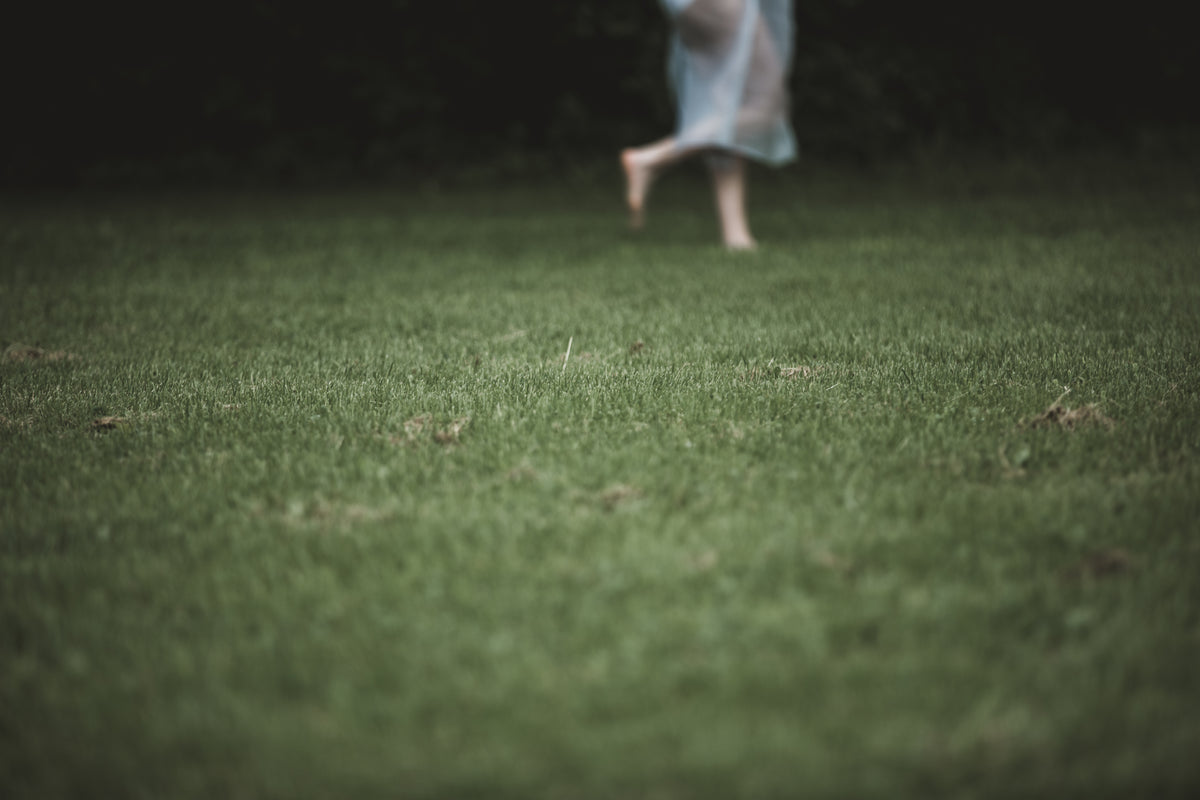 a figure in white netting runs across lawn