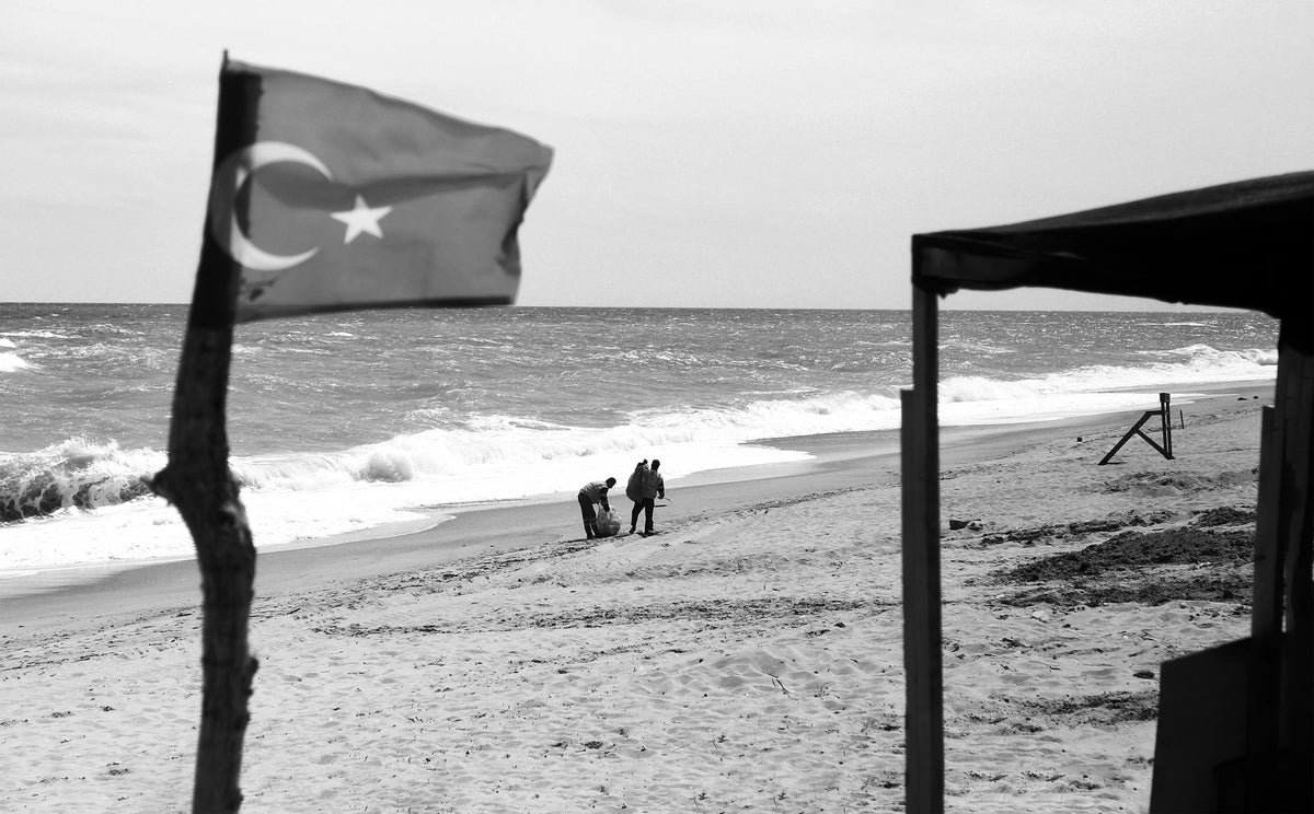 a flag and people on a beach in black and white