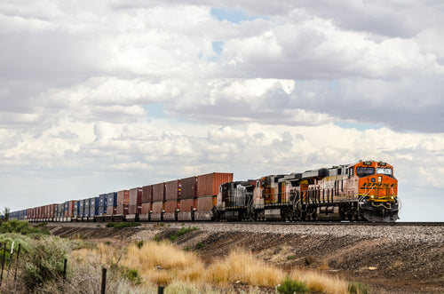a freight train hauls containers through the plains